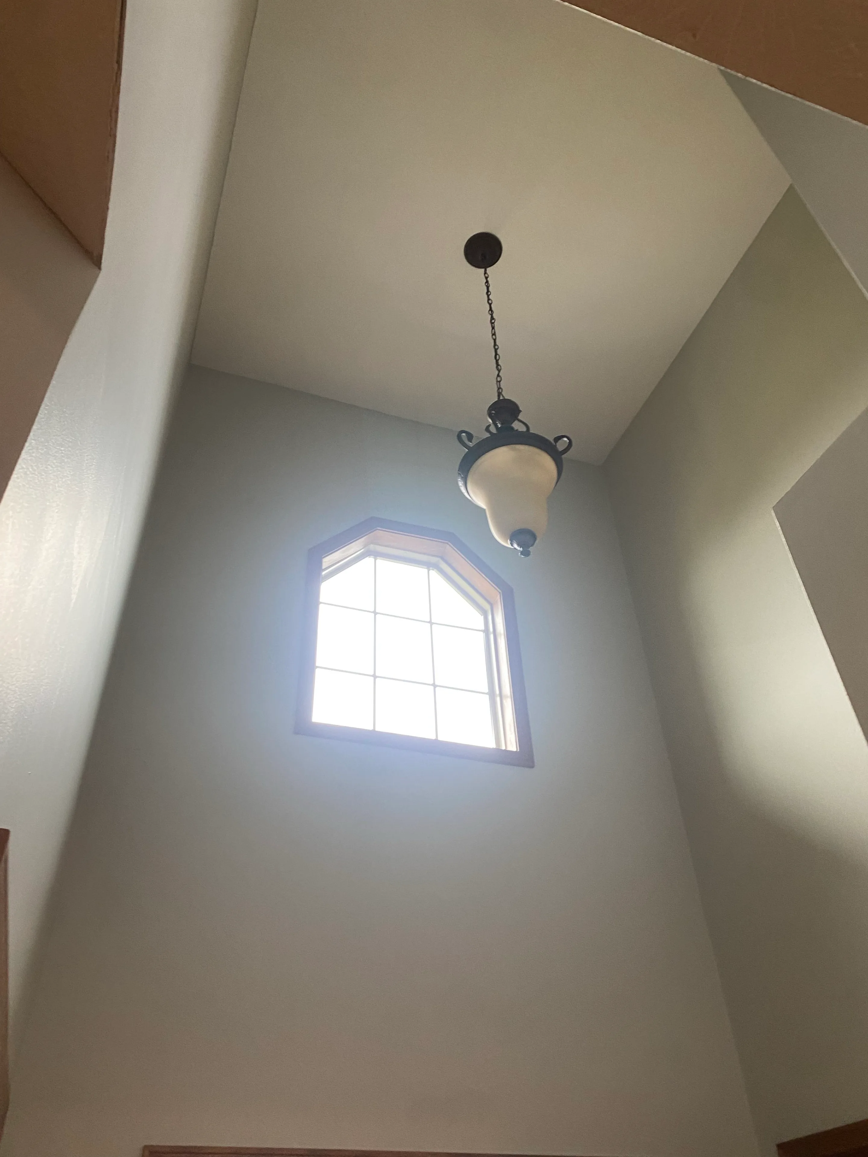 Freshly painted tall entry walls and ceiling around a high window and hanging light